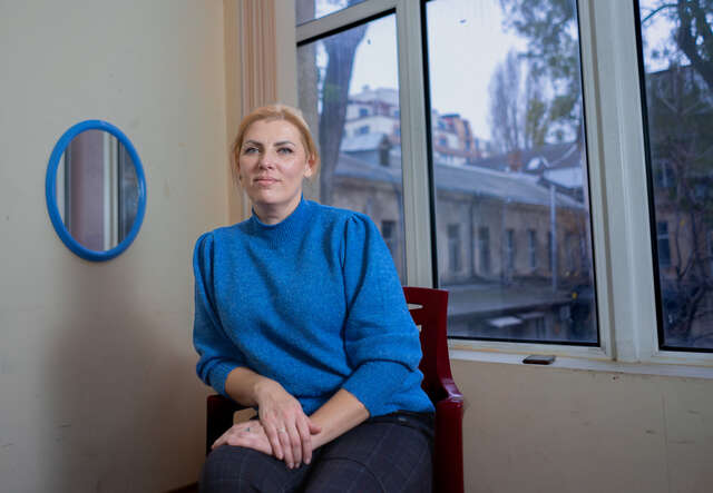 Eine Frau sitzt in der Ukraine und blickt in die Kamera.